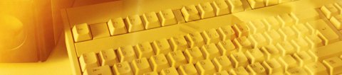 Long, yellow, rectangular picture of a keyboard with a light shining on it.