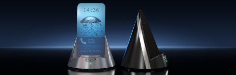 Silver triangular device with a mobile phone placed on it. The mobile phone screen displays a call coming in and a green light flashes below; the black iBell2 sits next to the silver model.