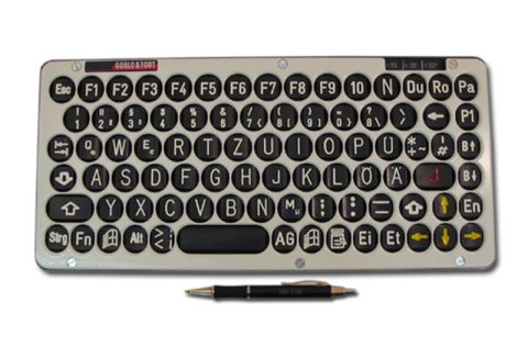 Large rectangular keyboard with black keys on beige background with pen in front.