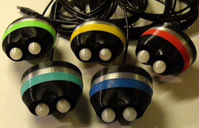 Five oval-shaped devices connected to cords, each with a different colored band around it.