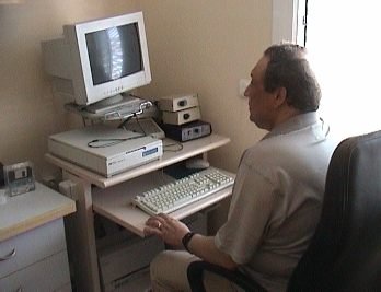 A user sits at a desk with a computer monitor and keyboard in front of him. The screen is black.