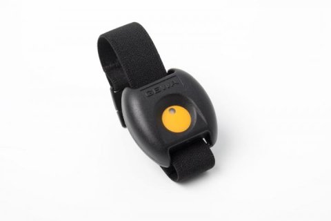 A small black rectangular device attached to a wristband with a yellow button in the middle.