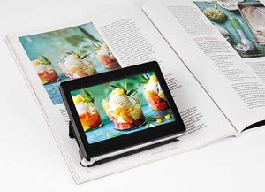 Picture of a small rectangular video screen sitting, using a stand, on an open book, with an image from the book magnified on the screen.