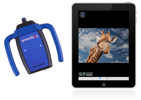 A blue oblong device with handles on either side and a small tubular opening at the top. Next to it is an iPad with an image of a giraffe's head and neck against the sky. 