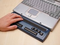 A blue braille keyboard attached to the bottom of a laptop.