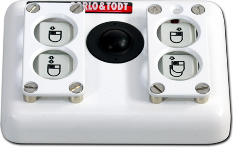 A small rectangular device with 4 buttons in a 1x2 layout on either side of a small, centered trackball. A mouse or double mouse is drawn on the buttons and a right or left click highlighted. Above the buttons on the right side is a led light indicator. This housing also showcases a raised finger-guard over the four buttons with each corner of the guard screwed to the housing.