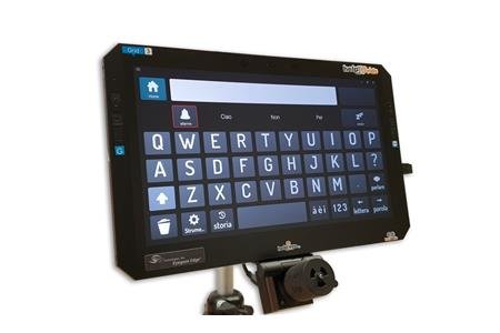 A tablet/monitor mounted on a vertical stand with a QWERTY keyboard and text box on the screen. Attached at the bottom of the tablet is a medium-sized cylindrical device with a small light in its center. There is a cord running from this device to the tablet.