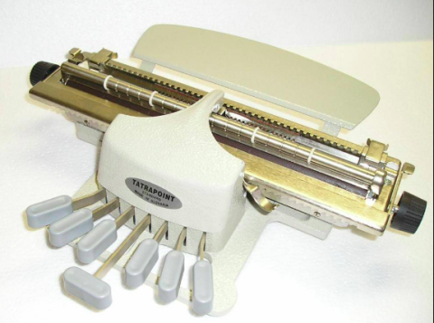 A Braille Perkins typewriter that has a white cover with restrictive key slots, embosser, paper rest, 6 keys, space bar, and black roller knobs.