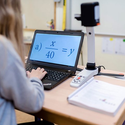 A laptop with the keyboard being used. On the screen is an algebraic equation written in an extremely large font.