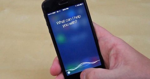 IPhone screen with Siri open and written on screen 'what can I help you with?'.