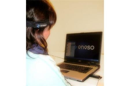A user wearing an enPathia strap around her head sitting in front of a laptop.