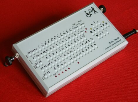 Wired, rectangular keyboard with legs and circular recessed keys.