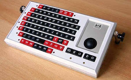 Wired, rectangular keyboard with legs and trackball on right.