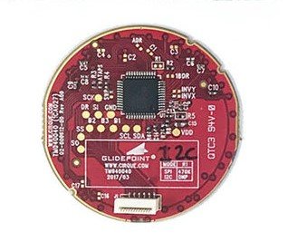 A red circular object with the circuit board of the trackpad exposed.