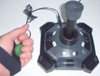 A black free standing device with a joystick in the center and an external button.