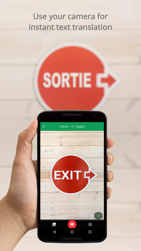 A user holds a phone over a red sign with white text to show the app translate the word "exit" into English.