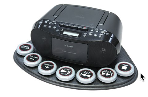 Boombox on a flat surface with seven large, round controls across the front edge.