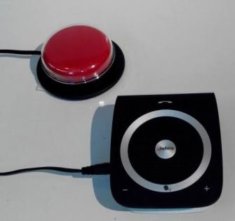 A black speaker with audio controls connected by wire to red, circle switch button.