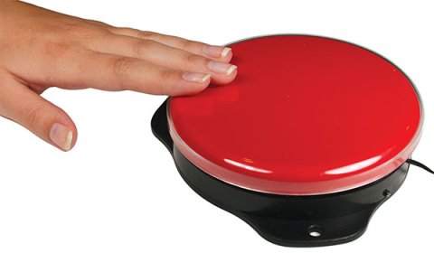 A user's hand presses a large, round, red switch, with a flat top and black colored base. 