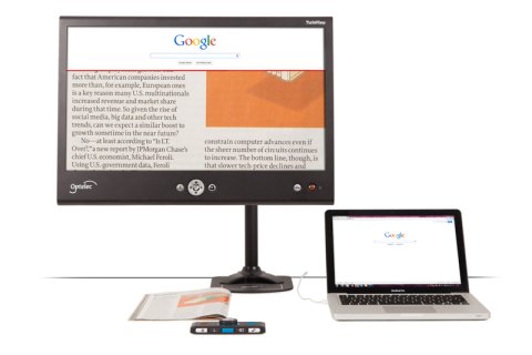 Large display monitor with a laptop next to it. Beneath the monitor on the desktop itself, there is a folded magazine. The monitor screen is displaying a zoomed-in view of the magazine. Across the top of the monitor screen, there is also a zoomed-in view of Google, which is also displayed on the laptop.