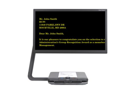 Large display monitor with a platform base underneath for placing documents and materials to magnify. The screen is black displaying high-contrast yellow font.