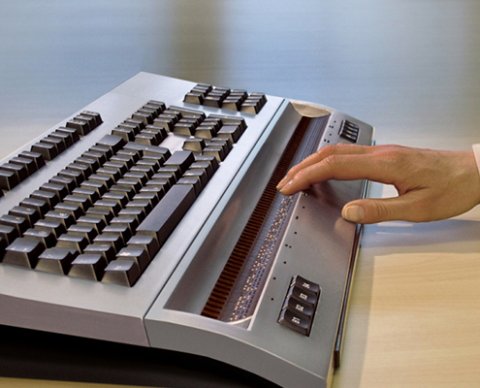 Hand on keyboard with black keys and a ledge beneath the keys.