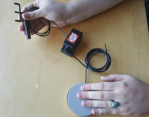 Person using laser with switch connection to button via square unit.