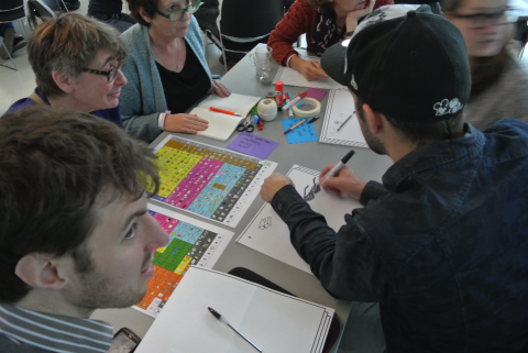 Volunteers sitting around a table and creating AAC grids on paper. 