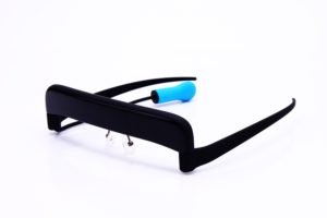 Black device resembling a headband or visor, with two arms that fit over the user's ears. A cable with a blue bite tip at the end is attached to the device. 