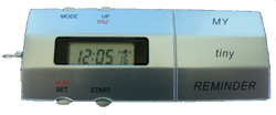 Small, long, and silver device with a small LCD panel displaying the time. The device features various small menu buttons. On the right-hand side, the device reads "My tiny reminder."