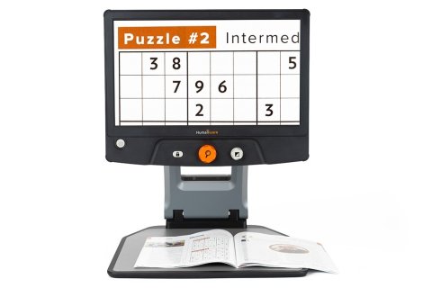 Large rectangular monitor displaying a magnified puzzle with open magazine resting on the stand below it.