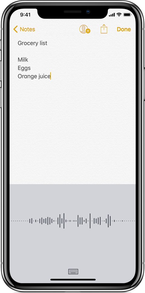 Screenshot of dictation on an iPhone in use, featuring the iOS Notes app displaying a grocery list, with the microphone in use as a user dictates another item to add to the list.