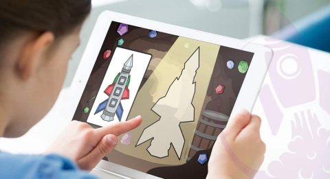 Child holding a tablet computer and pointing at an image of a rocket ship on the screen.