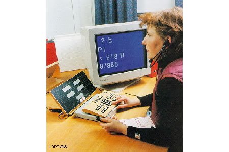 A woman wearing a headset and sitting in front of a computer monitor while using the LCD Reader.