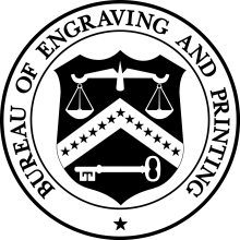 A circle with the words "Bureau of Engraving and Printing" printed in black around the top half of the circle. In the center of the circle, a black and white shield with an illustration of scales and a key.