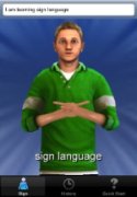 Screenshot of man in green long sleeve shirt making an ASL sign with two hands.