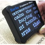 Small, handheld device with large screen displaying enlarged text when positioned over a newspaper.
