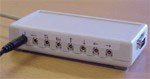 A rectangular device with eight ports for mini-jack jacks on one side and one port on the adjacent side.