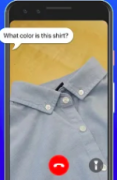 An iPhone with a buttoned collared shirt taking up most of the screen. Above it is a dialog bubble with the question, "what color is this shirt?". At the bottom of the phone's screen is a red circle with the phone icon for ending the call and next to that is a button-icon of a flashlight.