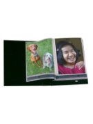 Open photo album with picture of two dogs on left side and girl smiling on right side.