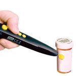 A device shaped like a pen that is labeling a medicine bottle with a yellow audio sticker. 