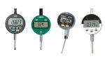Various models of digital indicators. They resemble small, round electronic devices with LCD digital display panels and small menu buttons on the front. They have small, thin probes resembling drill bits running down the center of the devices. One device is dark grey; one is green; one is grey and black; and a fourth is white and black.