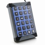 Small keyboard device the size and shape of a numeric keypad on a standard keyboard. There are twenty keys, which have various alphanumeric labels. The device base is black, and the keys have blue backlighting.