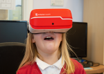 Young girl wearing orange virtual reality headset and looking up.