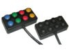 Two black rectangular devices with cords on the bottom. The box on the left has 8 buttons in blue, green, red, and yellow. The box on the right contains black buttons.