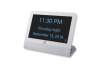 A white rectangular device with a black background and large blue text displaying the time, day, time of day, and date.