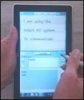 A person holding a Windows 7 tablet and writing on it with a stylus.